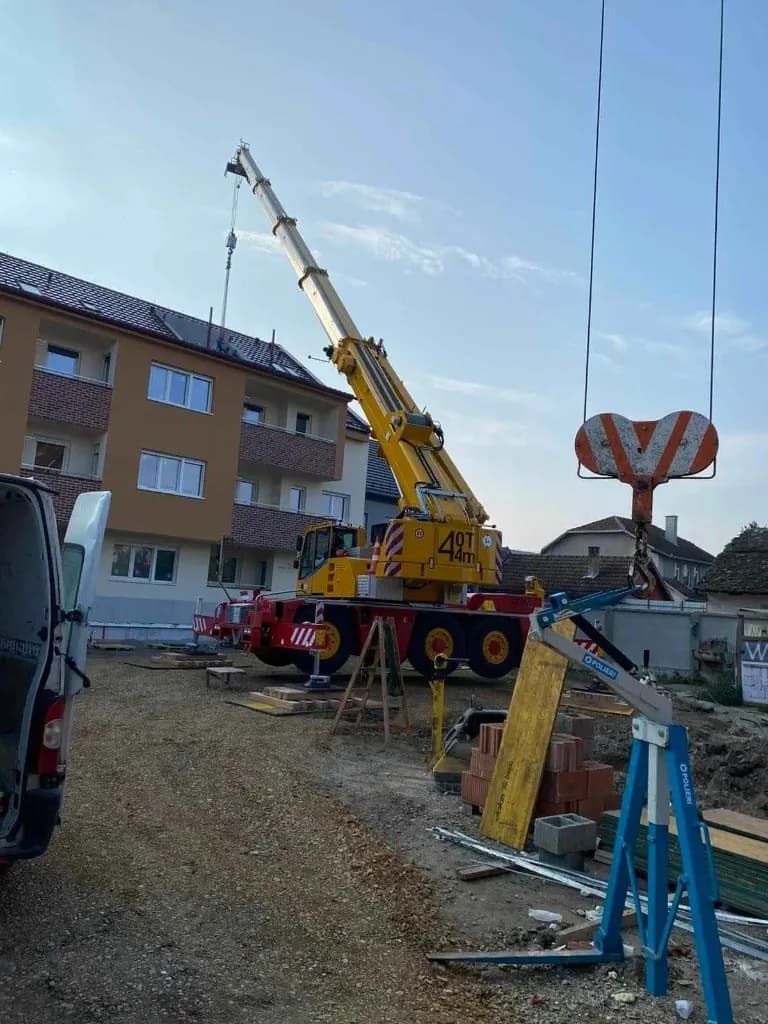 Autodizalica 40 tona sa izvučenim kranom podiže građevinski materijal na više spratova stambene zgrade u toku izgradnje — mobilni kran krak 44 m, iznajmljivanje autodizalice na gradilištu Srem i okolina, Metal Pro